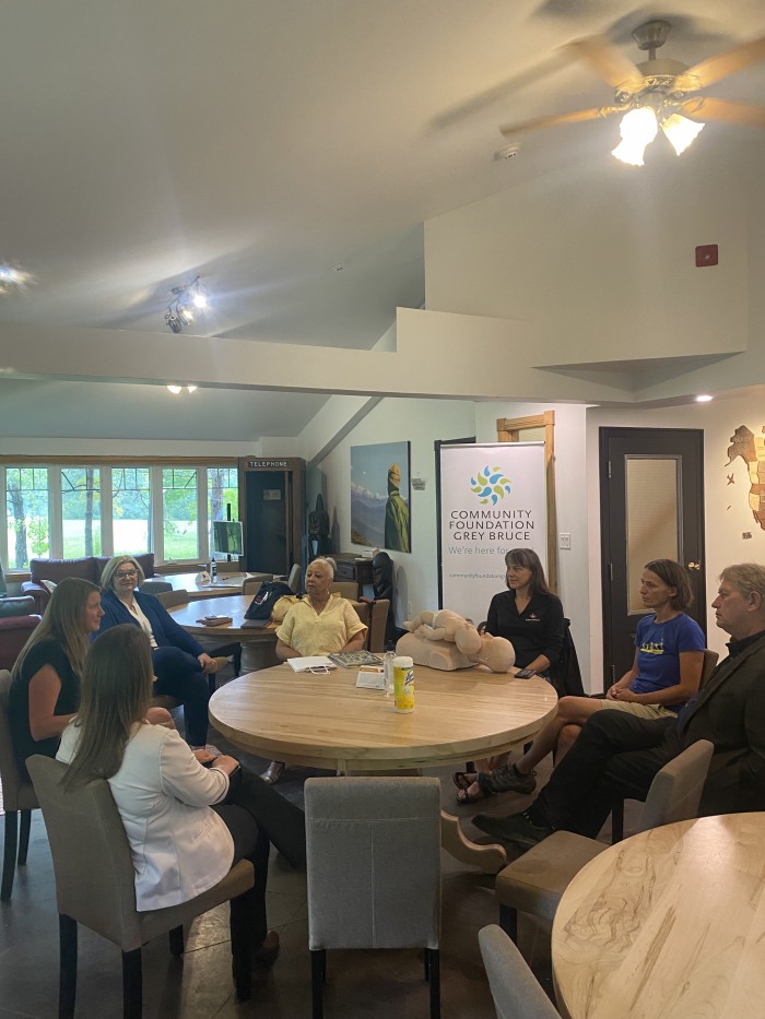 Everyone sitting around a table with Community Foundation banner behind them.