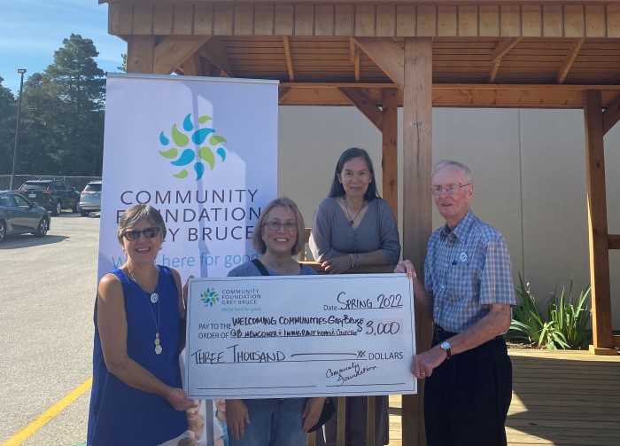 Welcoming Communities holding a large check in front of the Community Foundation banner