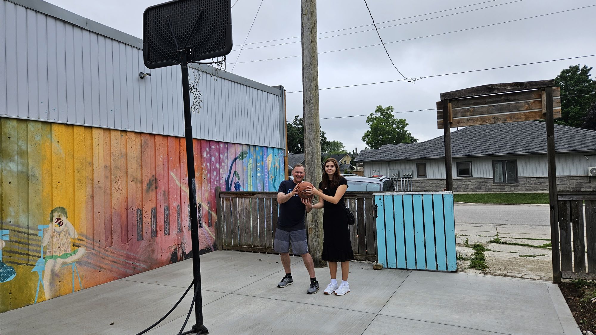 Greg Dow, Executive Director, Bruce Grey Mentorship and Mae MacNeil, Marketing & Communications Intern, Community Foundation Grey Bruce pose with a basketball to celebrate the front walk and yard refurbishment.